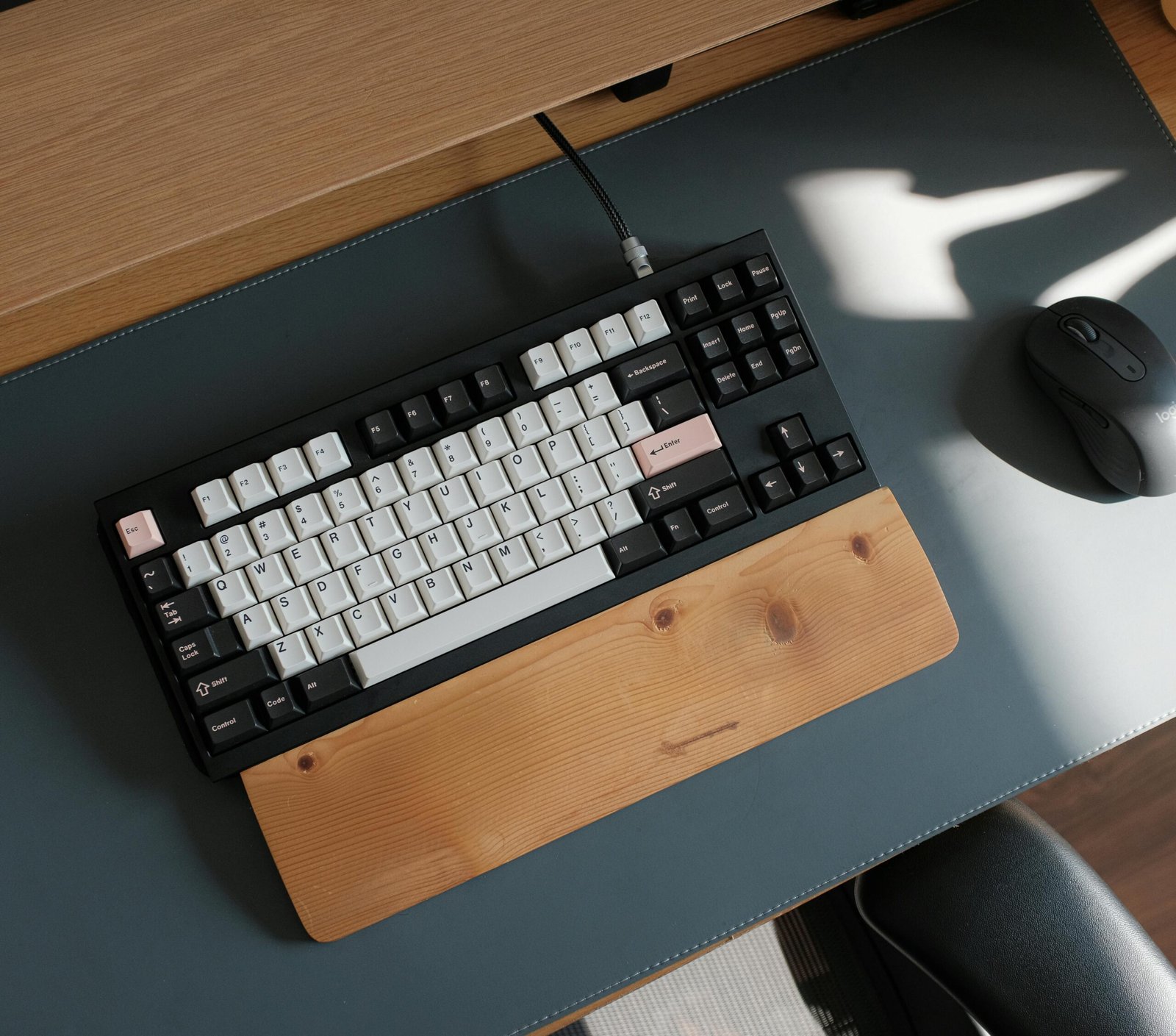 A sleek mechanical keyboard and mouse on a modern wooden desk in soft lighting.